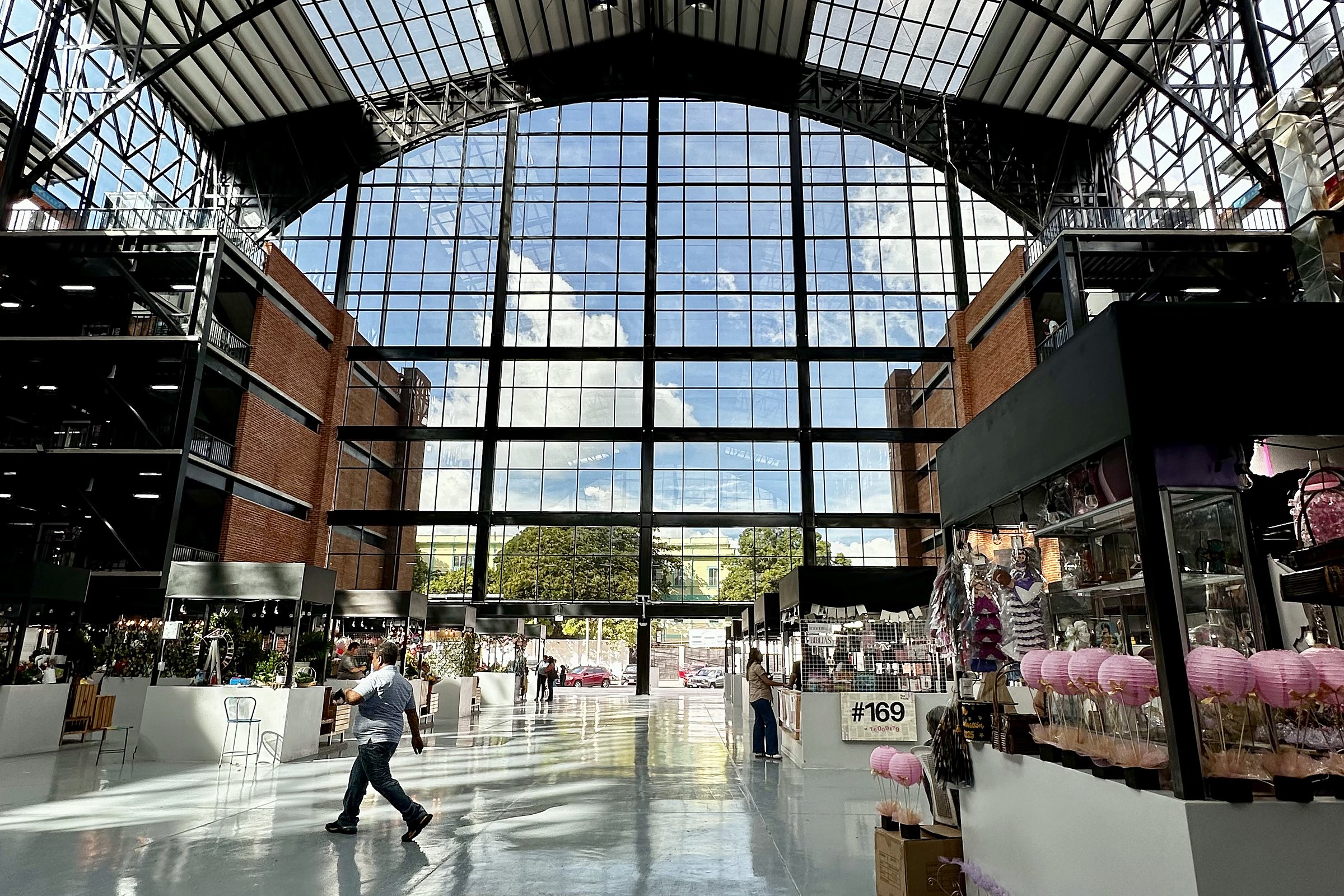 Shoppers walking through the bright, glass-roofed hall of the new Mercado San Miguelito in San Salvador